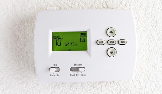 a wall-mounted thermostat with a digital display