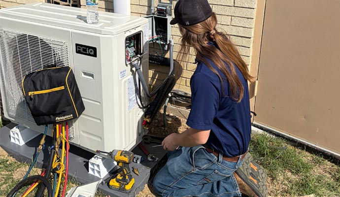Technician performing emergency AC repair on an outdoor unit