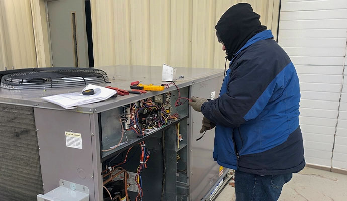 Technician repairing AC electrical components on an outdoor unit