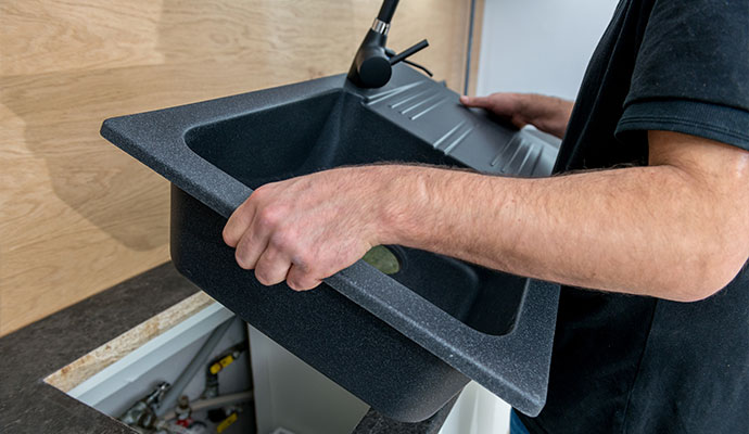Expert installing black composite kitchen sink