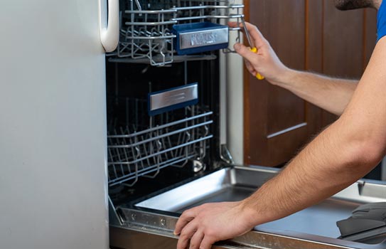 Worker repairing dishwasher leak