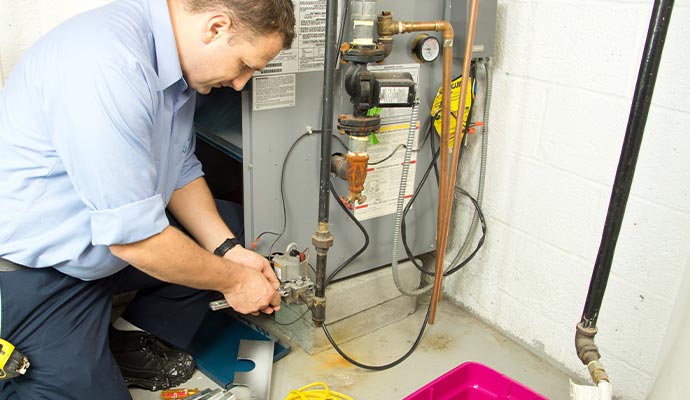 Technician repairing a residential furnace with a wrench