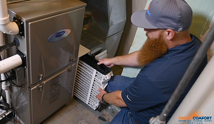 Technician replacing an air filter to prevent mold growth in a furnace