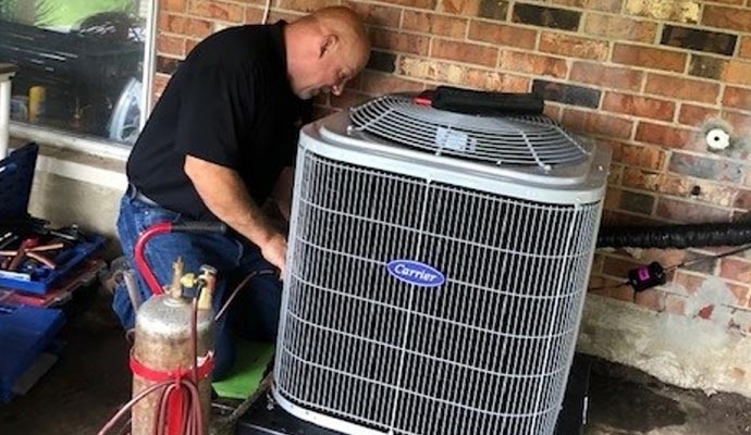 Technician servicing a Carrier outdoor HVAC unit