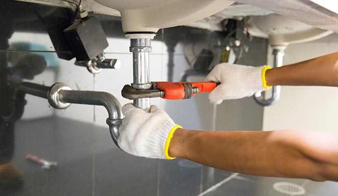 Professional worker repairing pipe under a sink