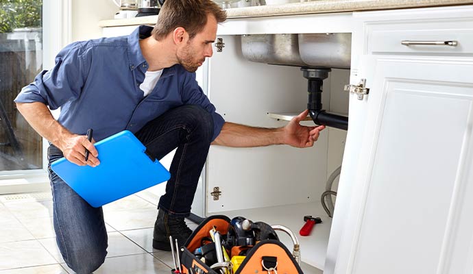 Plumber inspecting kitchen sink drain pipe