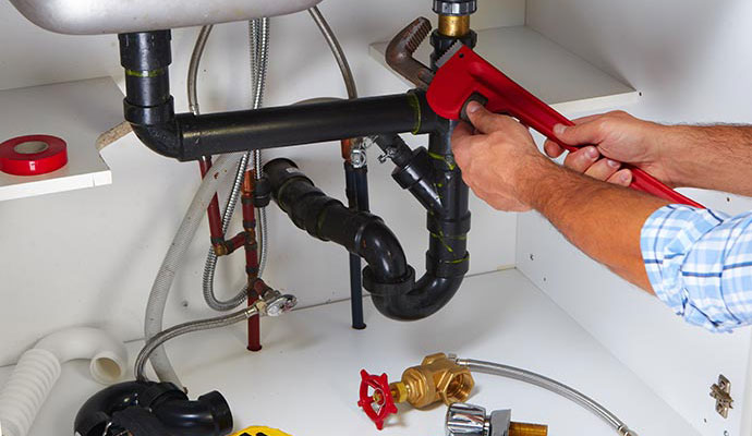 Professional worker repairing pipe under a sink