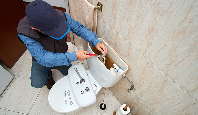 Technician repairing toilet tank components