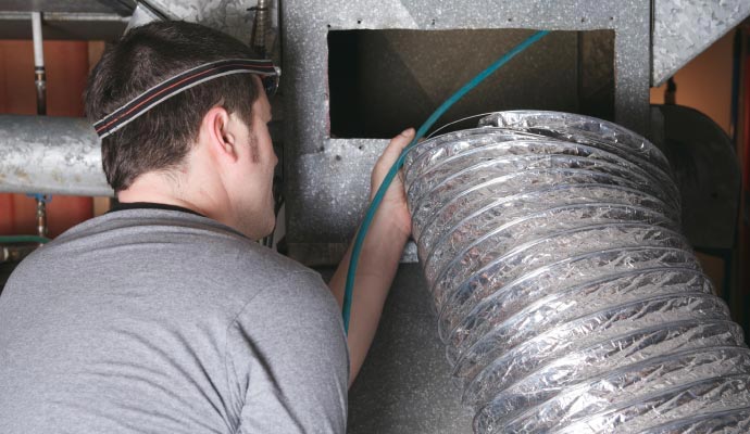 Technician servicing HVAC ductwork