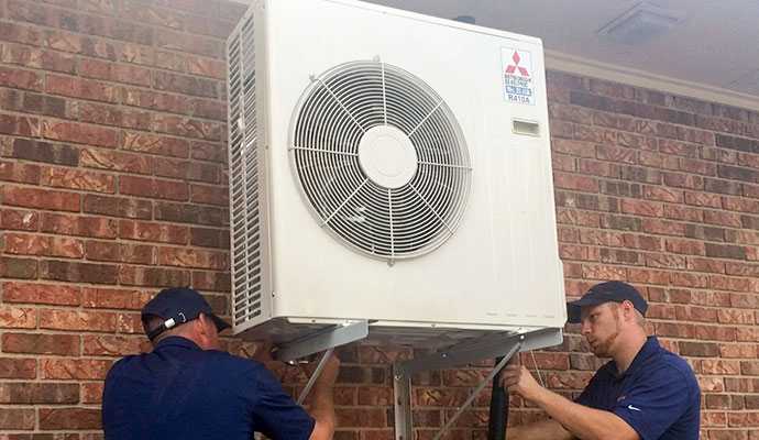 Two experts installing Mitsubishi outdoor ductless split system